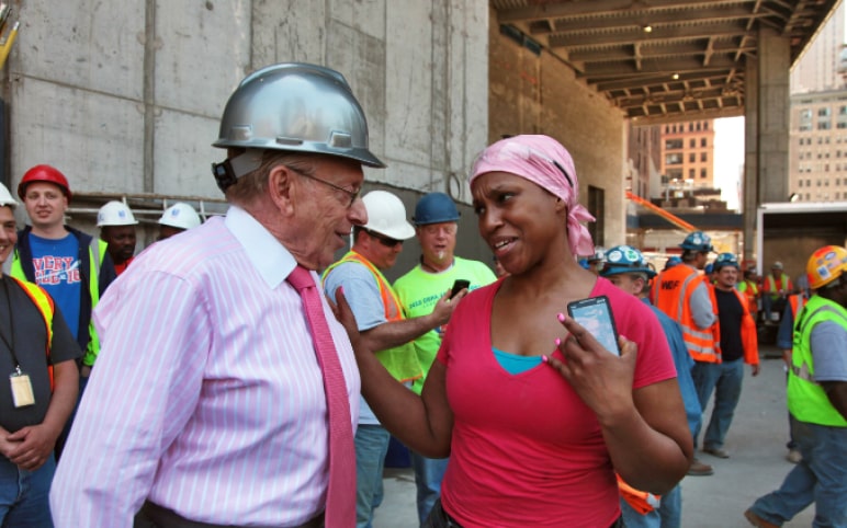 Larry Silverstein speaking to a community member on the floor of a construction site.